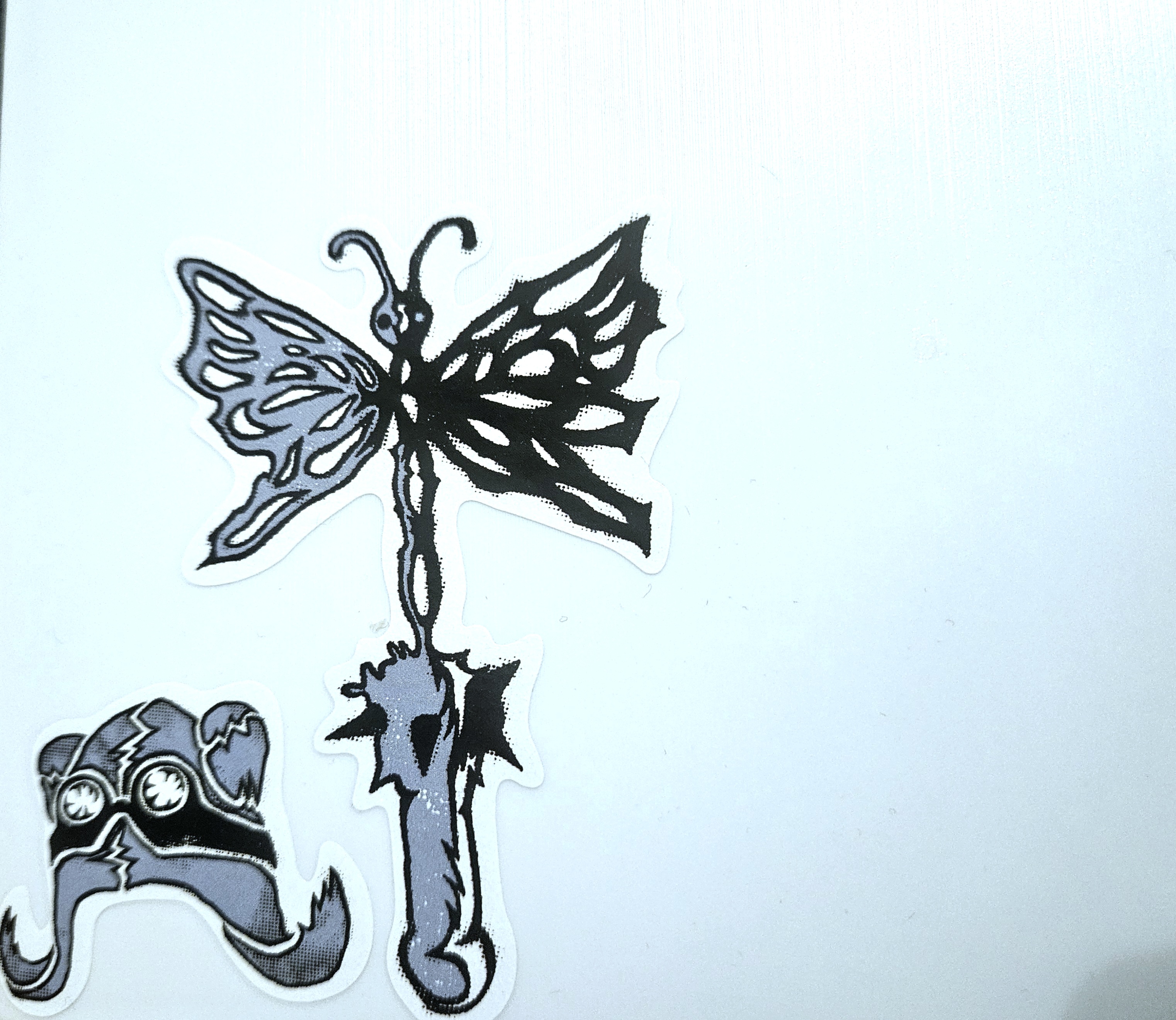 a white background with Yeule stickers of a black and blue pilot's hat and a mace with a butterfly for the spiky part